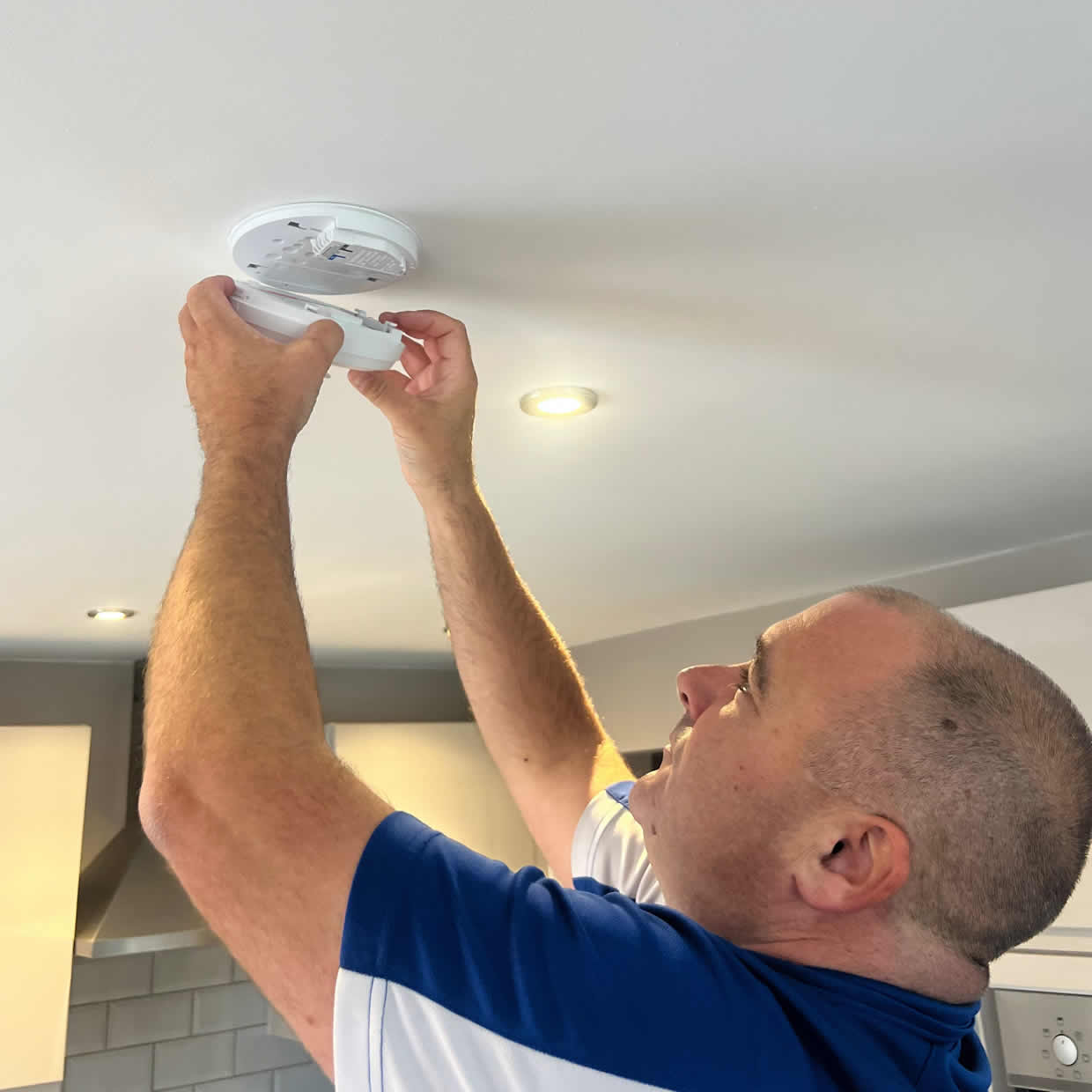 Smoke alarm installer fitting an alarm in a Droylsden property